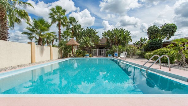 A rectangular swimming pool with a clear blue water surface, surrounded by palm trees and a fence. - Knights Inn Arcadia (Arcadia)