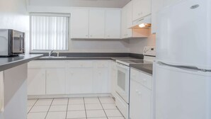A kitchen with white cabinets, a refrigerator, a microwave, and a stove. - Knights Inn Arcadia (Arcadia)