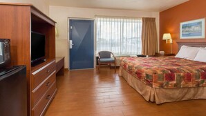 A hotel room with a bed, a television, a desk, a chair, and a door. - Knights Inn Arcadia (Arcadia)