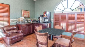 A cozy kitchen with a dining area, featuring a coffee machine, a refrigerator, and a framed picture on the wall. - Knights Inn Arcadia (Arcadia)