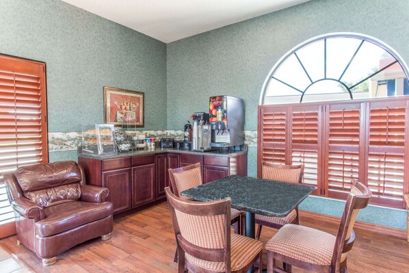 A cozy kitchen with a dining area, featuring a coffee machine, a refrigerator, and a framed picture on the wall.