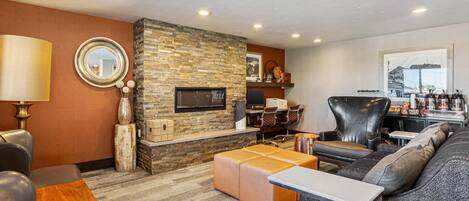 A modern living room with a stone fireplace, leather furniture, and a large mirror.