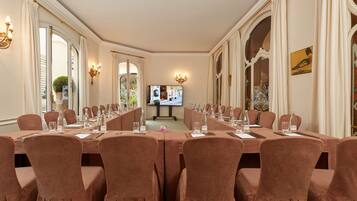 Une salle de conférence équipée de longues tables, de chaises et d’un écran de télévision.