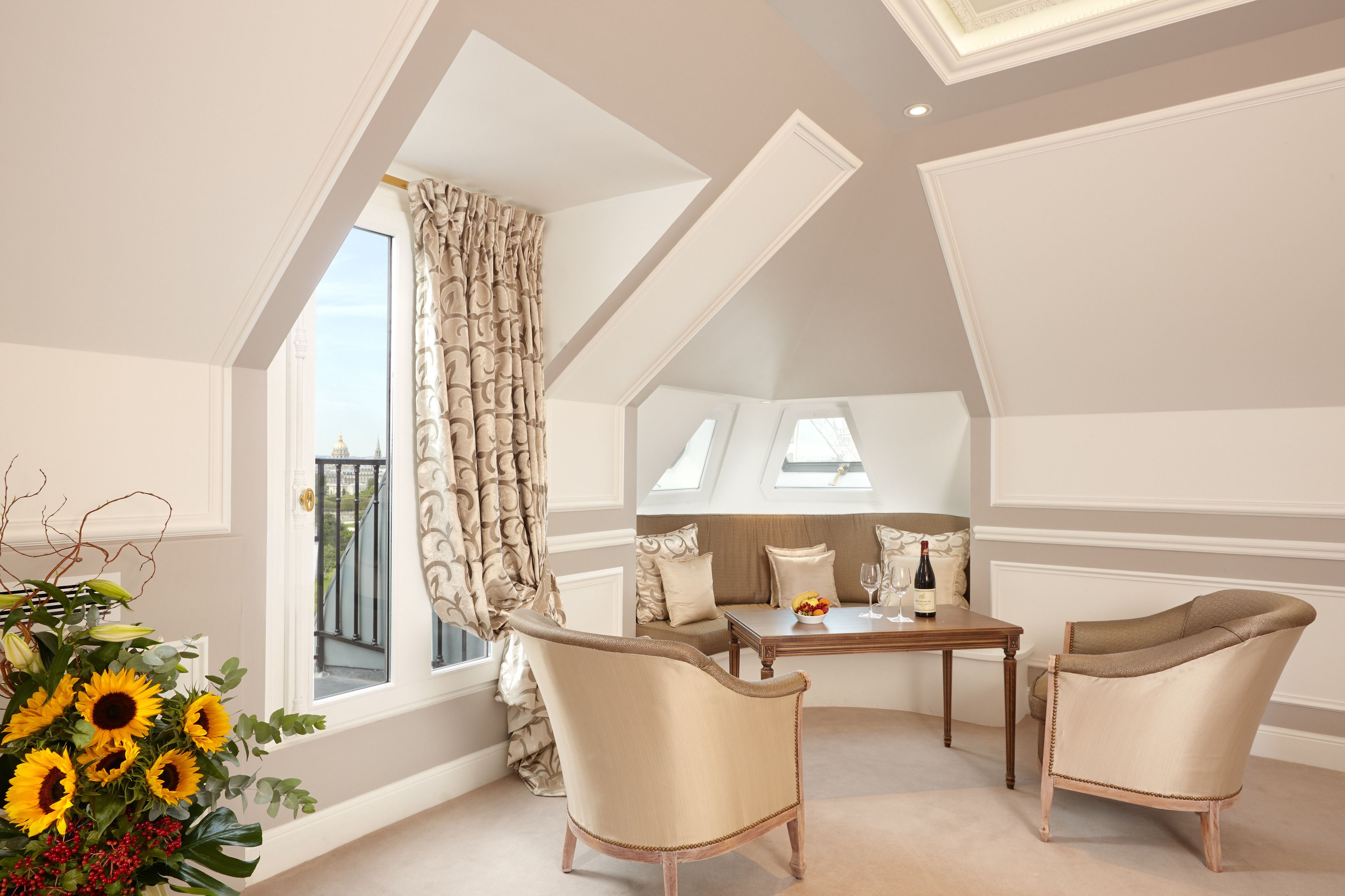 A room with a high ceiling, a dining table with chairs, a sofa, and a large window with curtains.