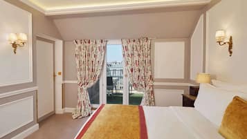 A hotel room with a bed, a window with curtains, a balcony, and wall sconces.