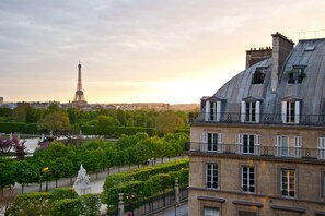 A view of the Eiffel Tower from a building with a sloped roof, a statue in the foreground, and a park with trees and a fountain. - Hotel Regina Louvre (Paris)