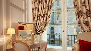 Una habitación de hotel con un ventanal grande, un escritorio de madera con un espejo, una silla y un sofá.