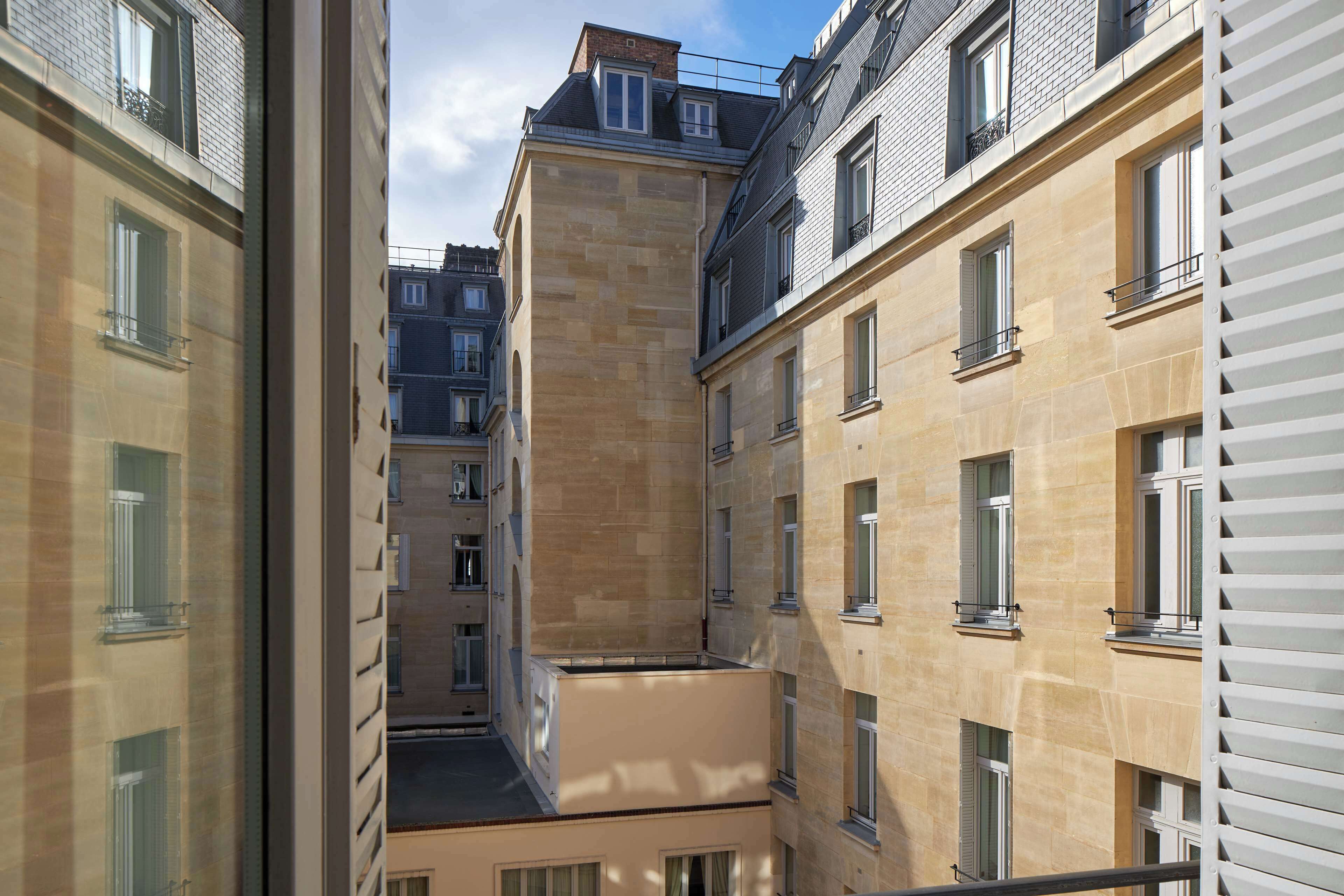 A narrow alleyway between buildings with multiple windows and balconies.