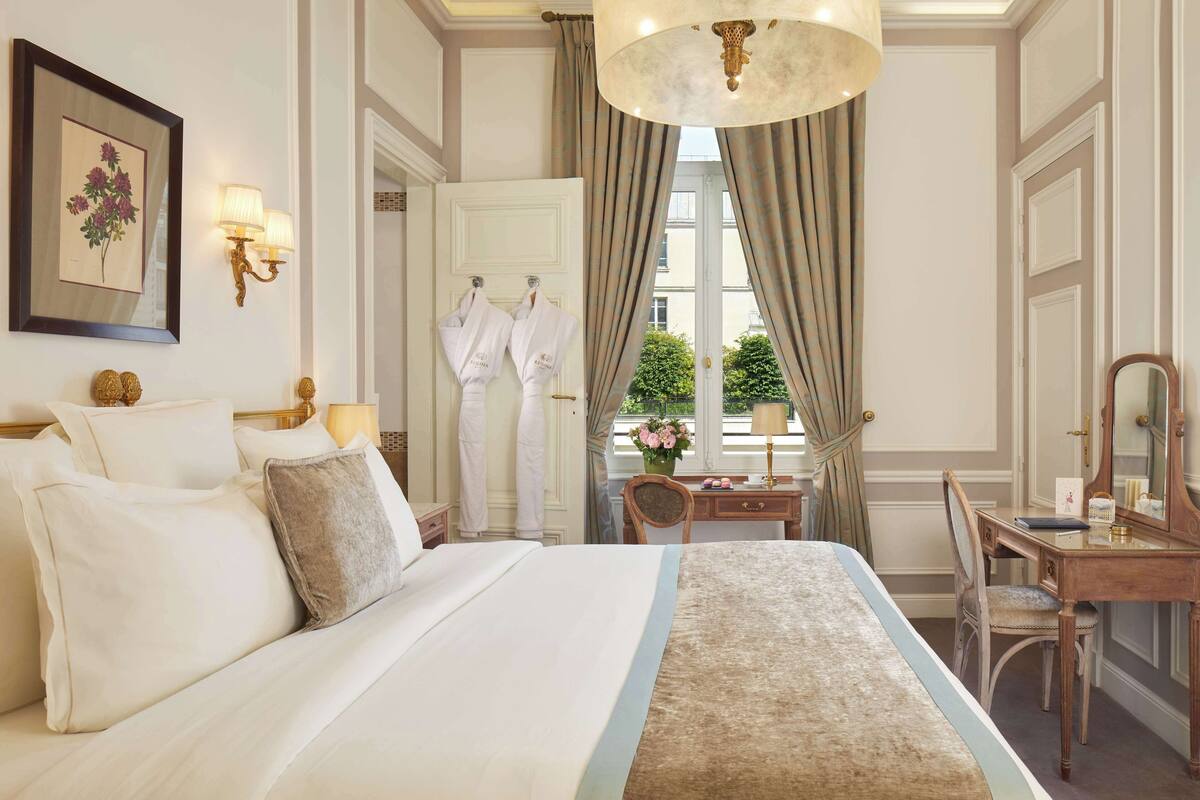 A hotel room with a large bed, a desk with a mirror, and a window with curtains.