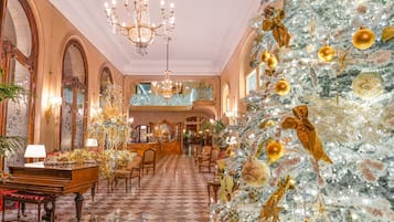 Um hall imponente com uma grande árvore de Natal, lustres e decoração requintada.