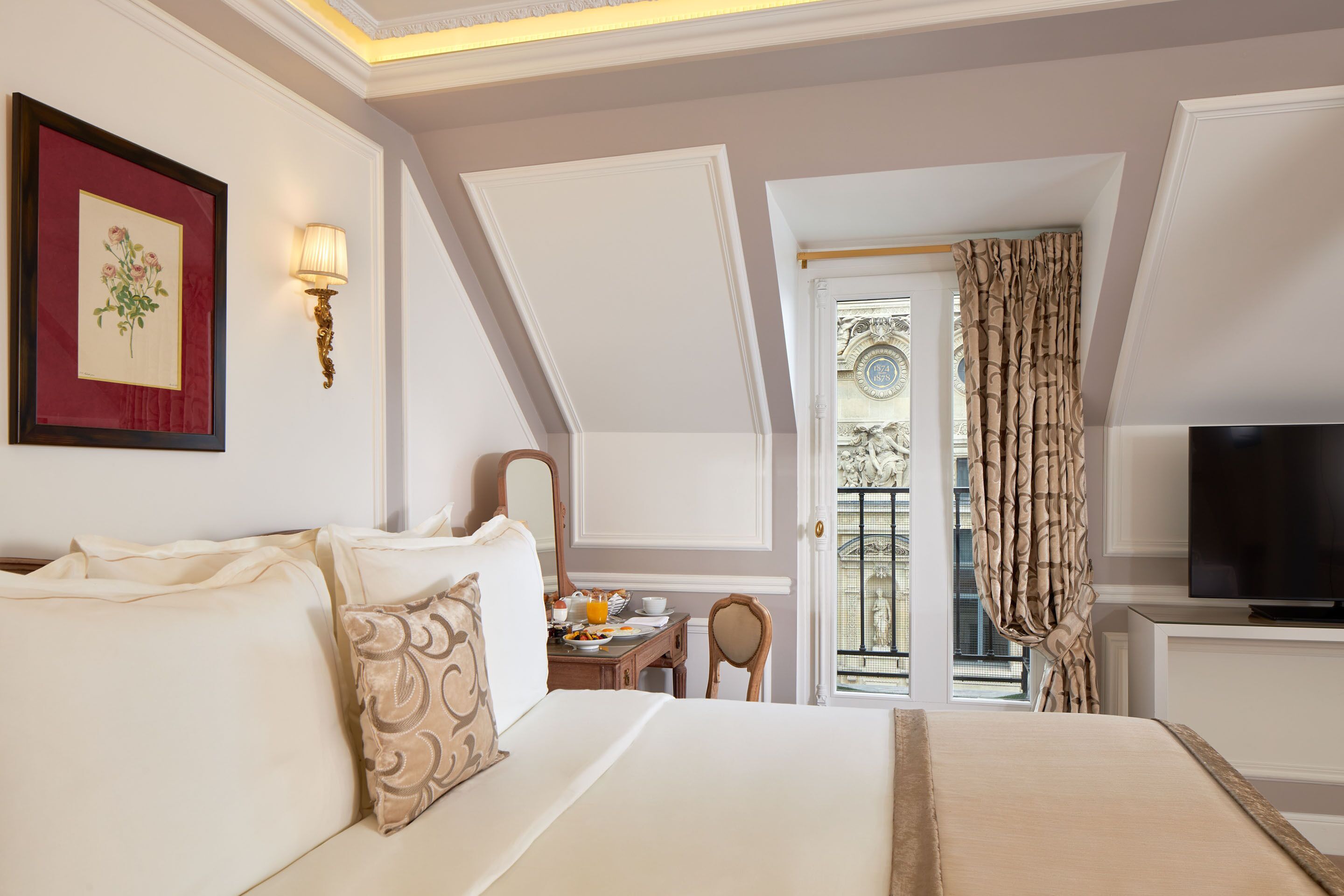 Ein Hotelzimmer mit einem Bett, einem Schreibtisch mit Frühstücksangeboten, einem Fernseher und einem Balkon mit Blick.