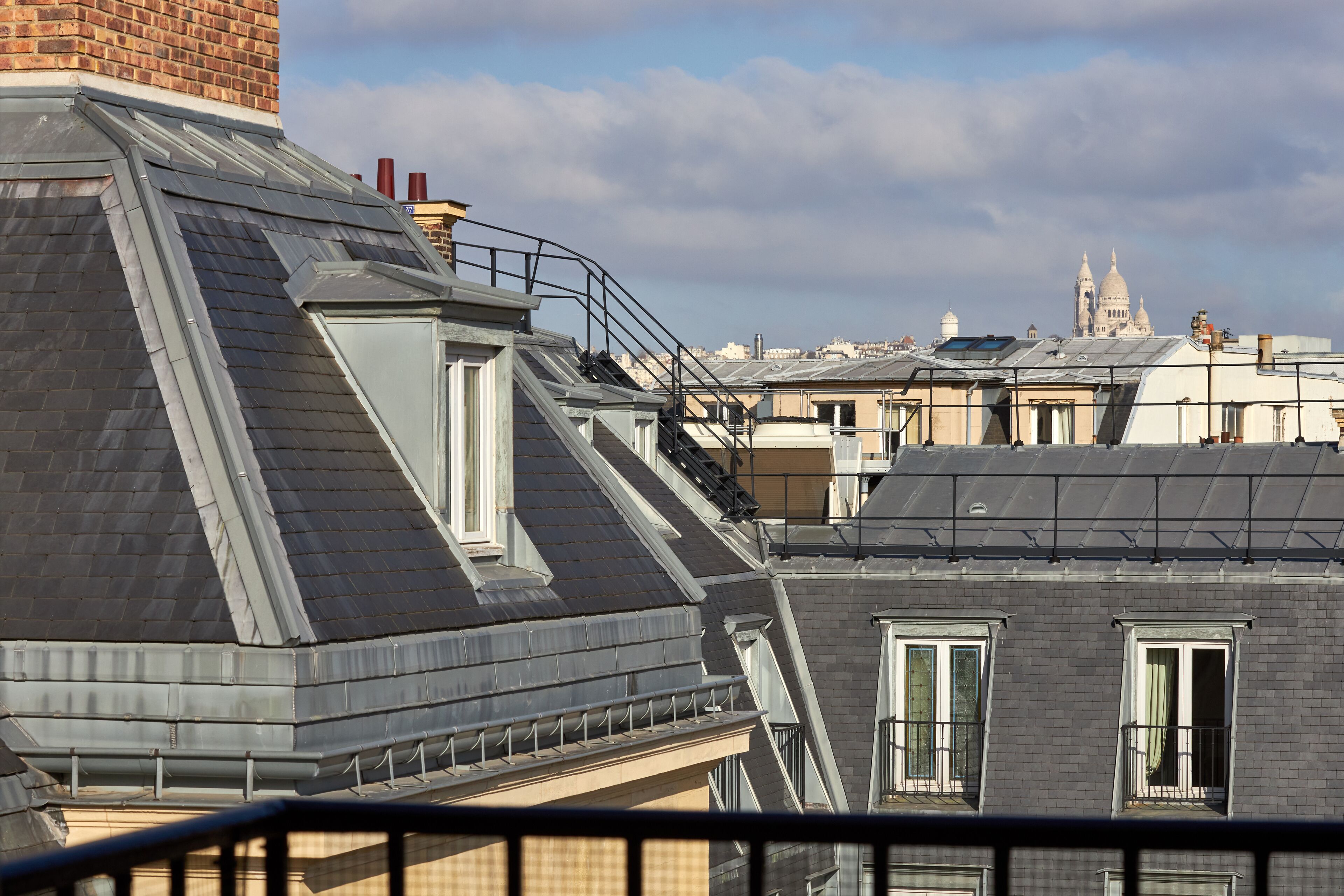 A residential building with a sloped roof, dormer windows, and a brick chimney.