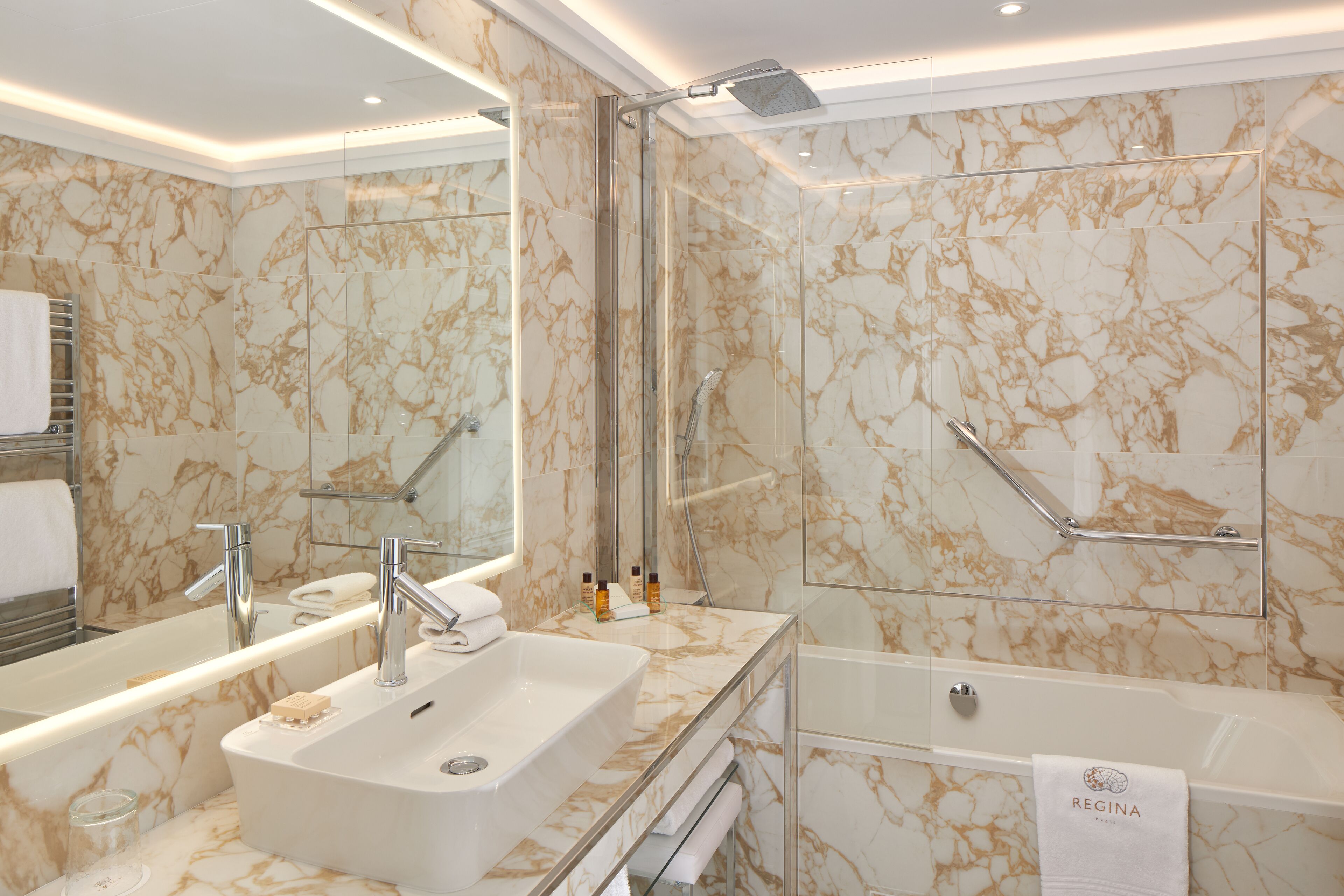 A modern bathroom with a marble vanity, a separate shower area, and a glass-enclosed tub.