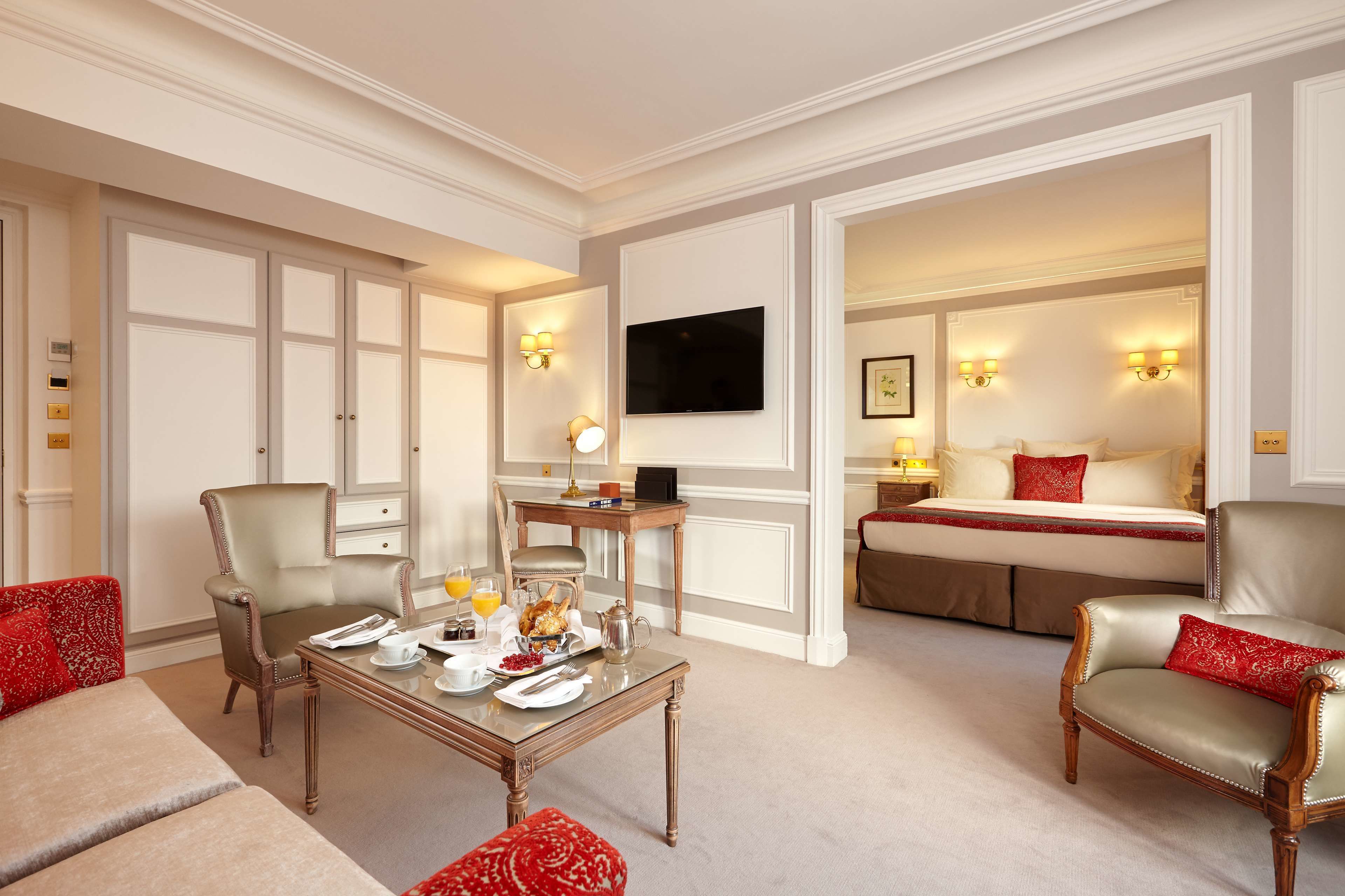 A hotel room with a dining area, a bed, and a television.