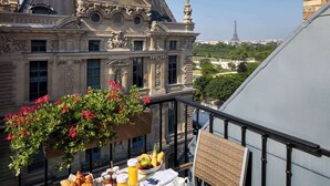 Un balcón con una mesa preparada para el desayuno, con vistas a un edificio histórico y la Torre Eiffel.