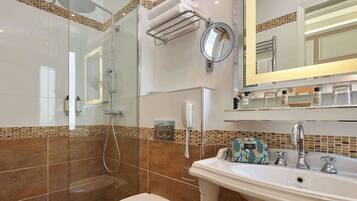 A bathroom with a glass-enclosed shower, a toilet, a sink with a mirror, and a towel rack.