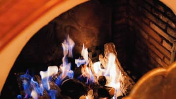 Un gros plan d’une cheminée avec des bûches qui brûlent et des flammes bleues.