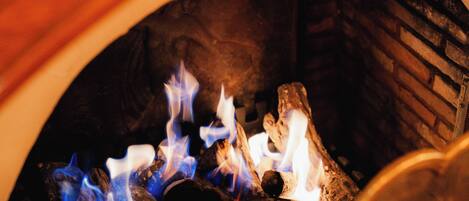 Primer plano de una chimenea con leña ardiendo y llamas azules.