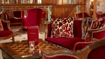 Una habitación lujosa con una mesa a cuadros, muebles tapizados en rojo y una vela pequeña.