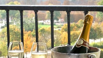 Un balcón con vistas a la Torre Eiffel, una botella de champán, dos copas y macarons sobre una mesa.
