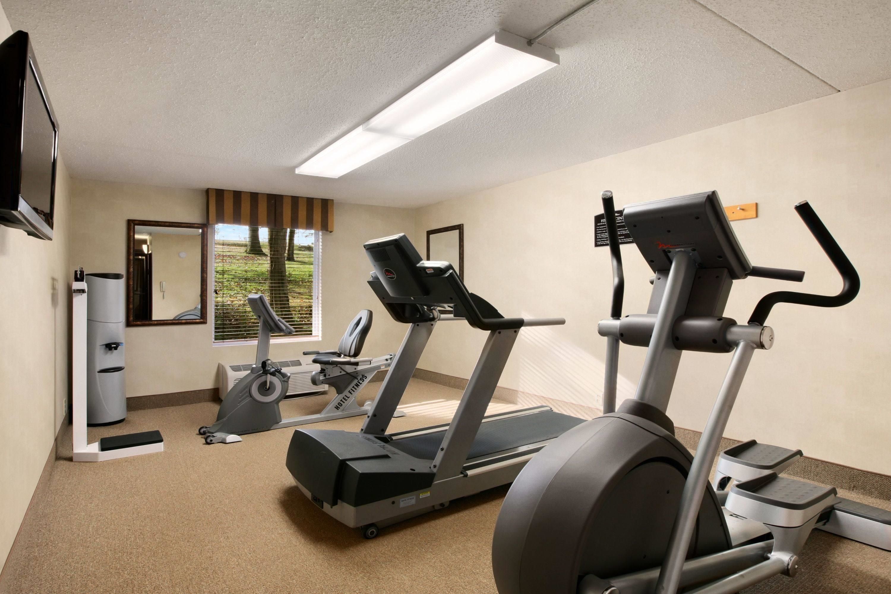A hotel fitness room with treadmills, a stationary bike, and a mirror.