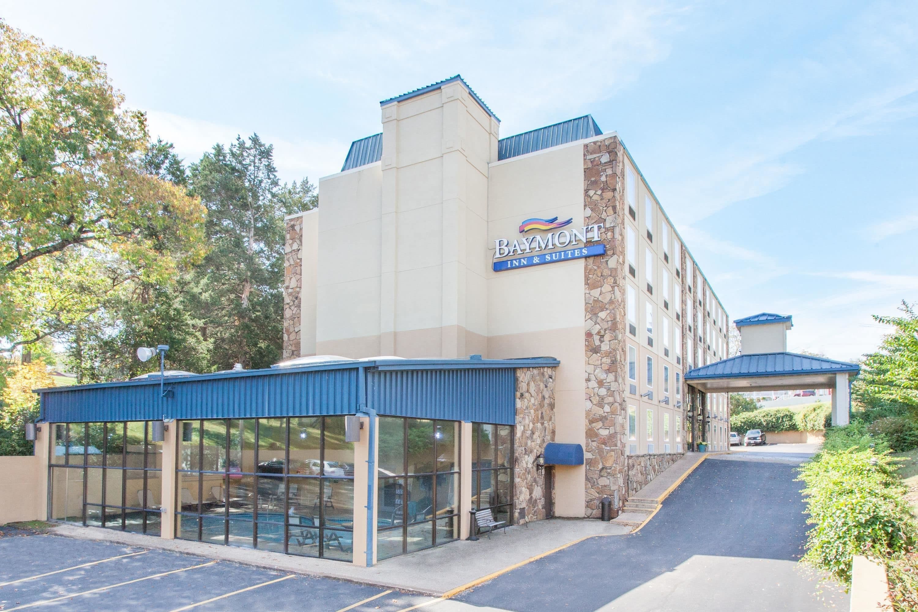 Een Baymont Inn & Suites gebouw met een stenen gevel, blauw dak en een overdekte entree.
