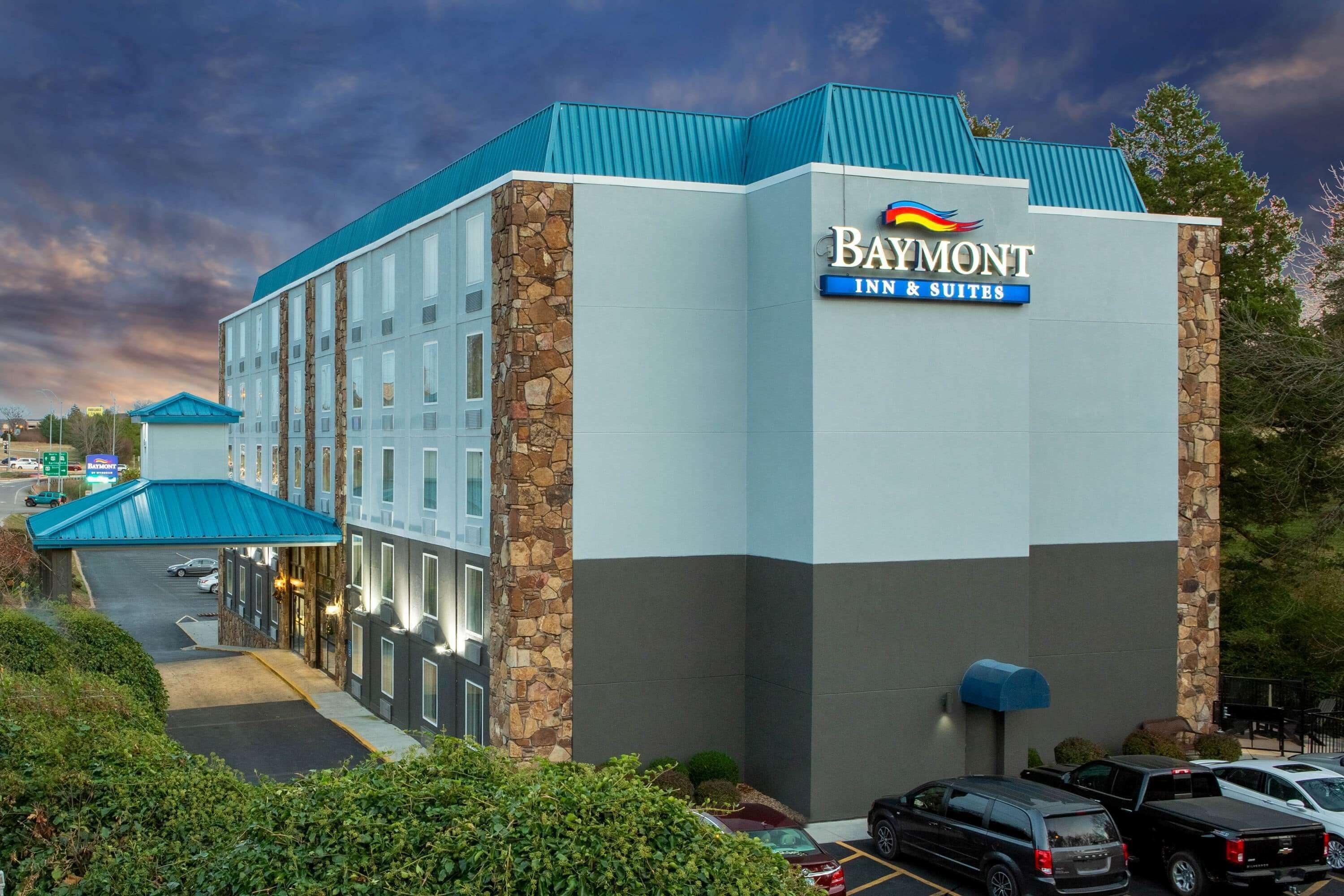 Baymont Inn & Suites -hotellin rakennus, jossa on kiviverhous, sininen katto ja kyltti, jossa näkyy hotellin nimi.