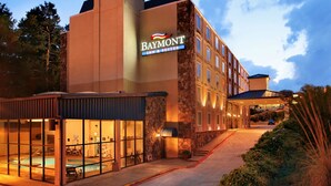 A Baymont Inn & Suites building with a pool area, stone facade, and multiple windows.