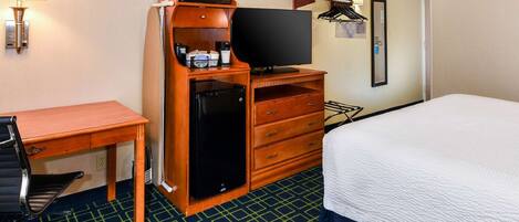 A hotel room with a bed, a desk with a chair, a television, a mini-fridge, and a microwave.