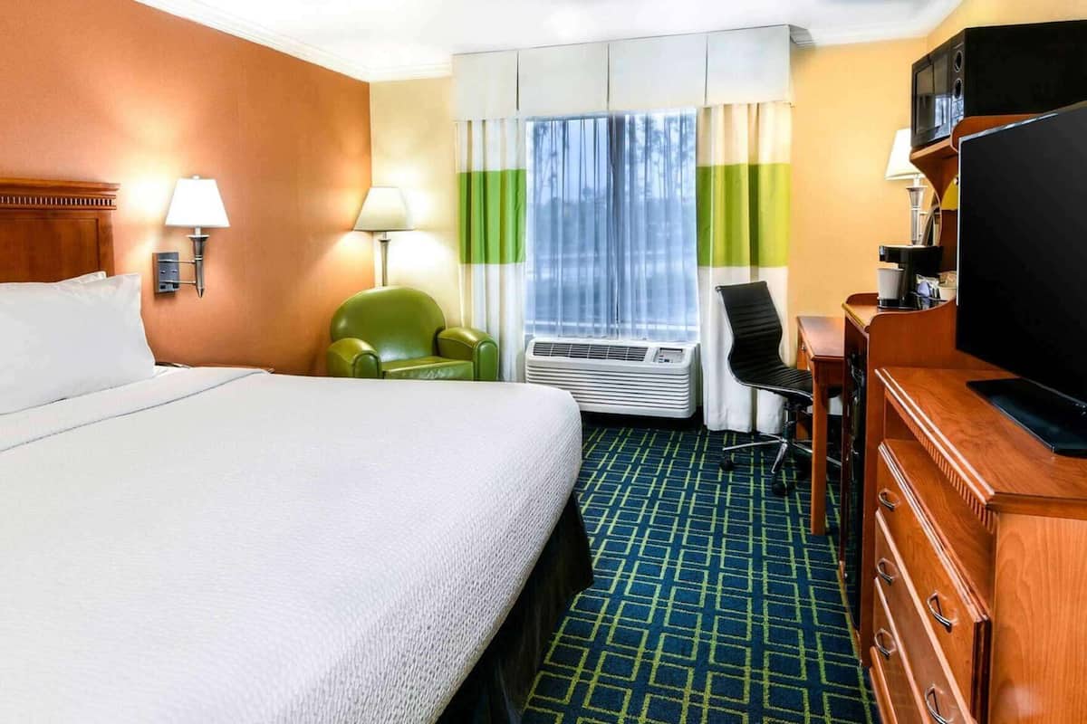 Une chambre d’hôtel équipée d’un lit, d’un bureau, d’une chaise, d’un climatiseur et d’un téléviseur.