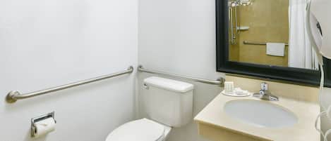 Un baño pequeño con inodoro, lavamanos, espejo y zona de ducha.