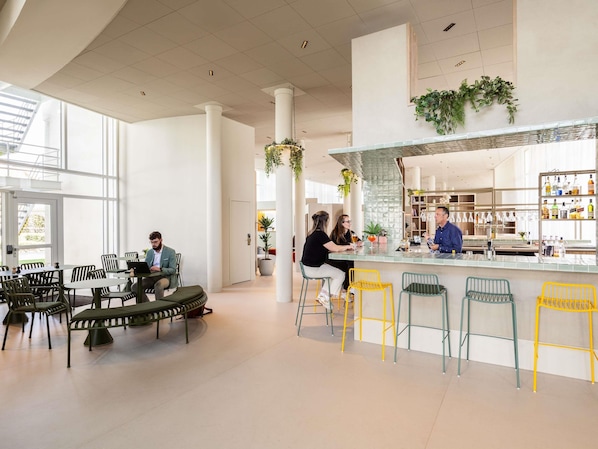 A modern interior with a bar area, seating, and a staircase leading to an outdoor area. - ibis Styles Brugge Centrum (Bruges)