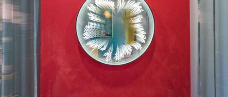 A circular wall art with a central light fixture, two blue cushioned seating areas, and a red wall.