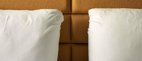 Dos almohadas blancas sobre una pared marrón texturizada.