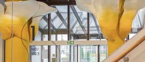 A modern interior with a glass door entrance, a visible exit sign, and a metal structure.