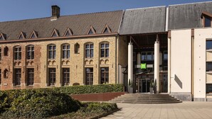 A building with a traditional brick facade, a modern glass entrance, and a clear sky. - ibis Styles Brugge Centrum (Bruges)