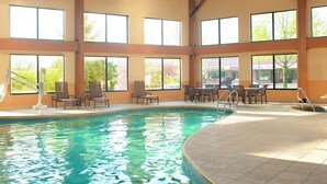 An indoor swimming pool with clear water, surrounded by large windows and furnished with chairs and tables. - Sheraton Bucks County Langhorne (Langhorne)
