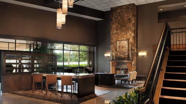 A modern lobby with a stone fireplace, a bar area, and a staircase. - Sheraton Bucks County Langhorne (Langhorne)