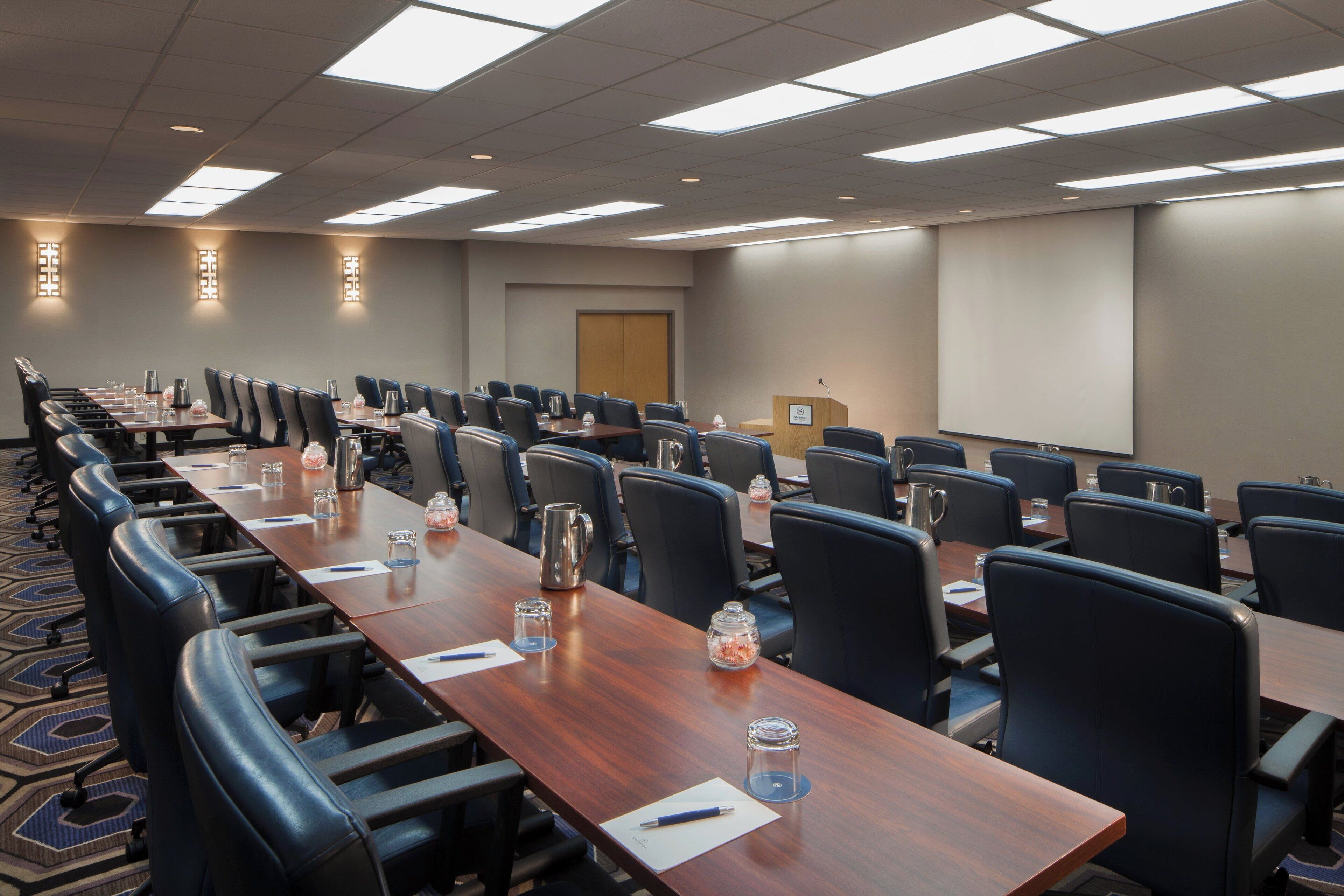 A conference room with long tables, chairs, and a podium.