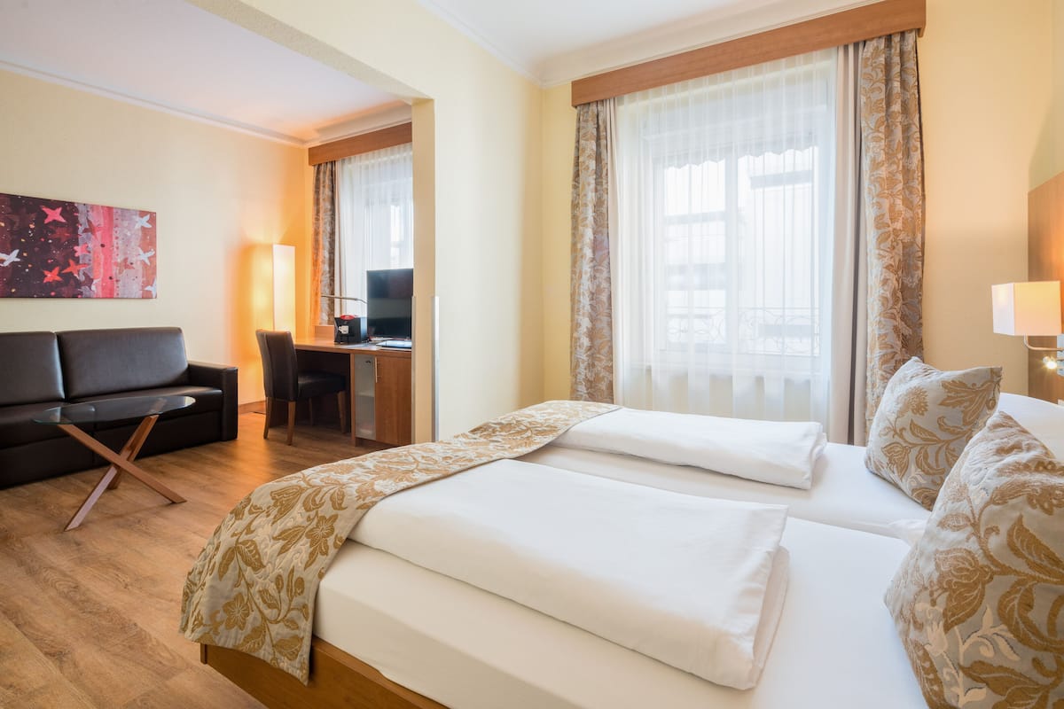 Habitación de hotel con dos camas, un escritorio, un sofá y un televisor.