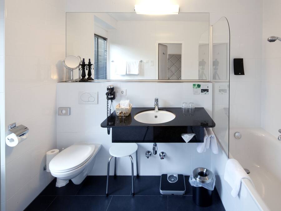 A modern bathroom with a white toilet, black sink, and a bathtub.