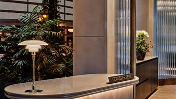 A reception desk with a nameplate, a lamp, and a potted plant.