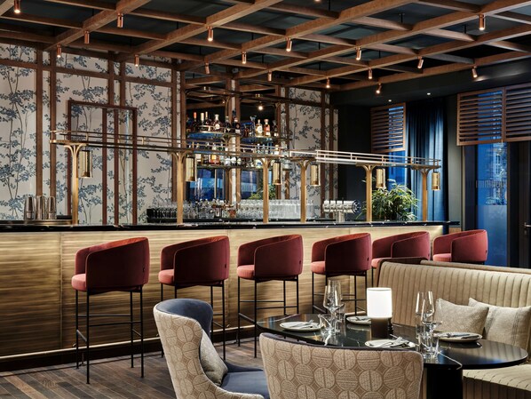 A bar area with wooden beams, bar stools, and a bar counter. - Radisson Collection Hotel, Berlin (Berlin)