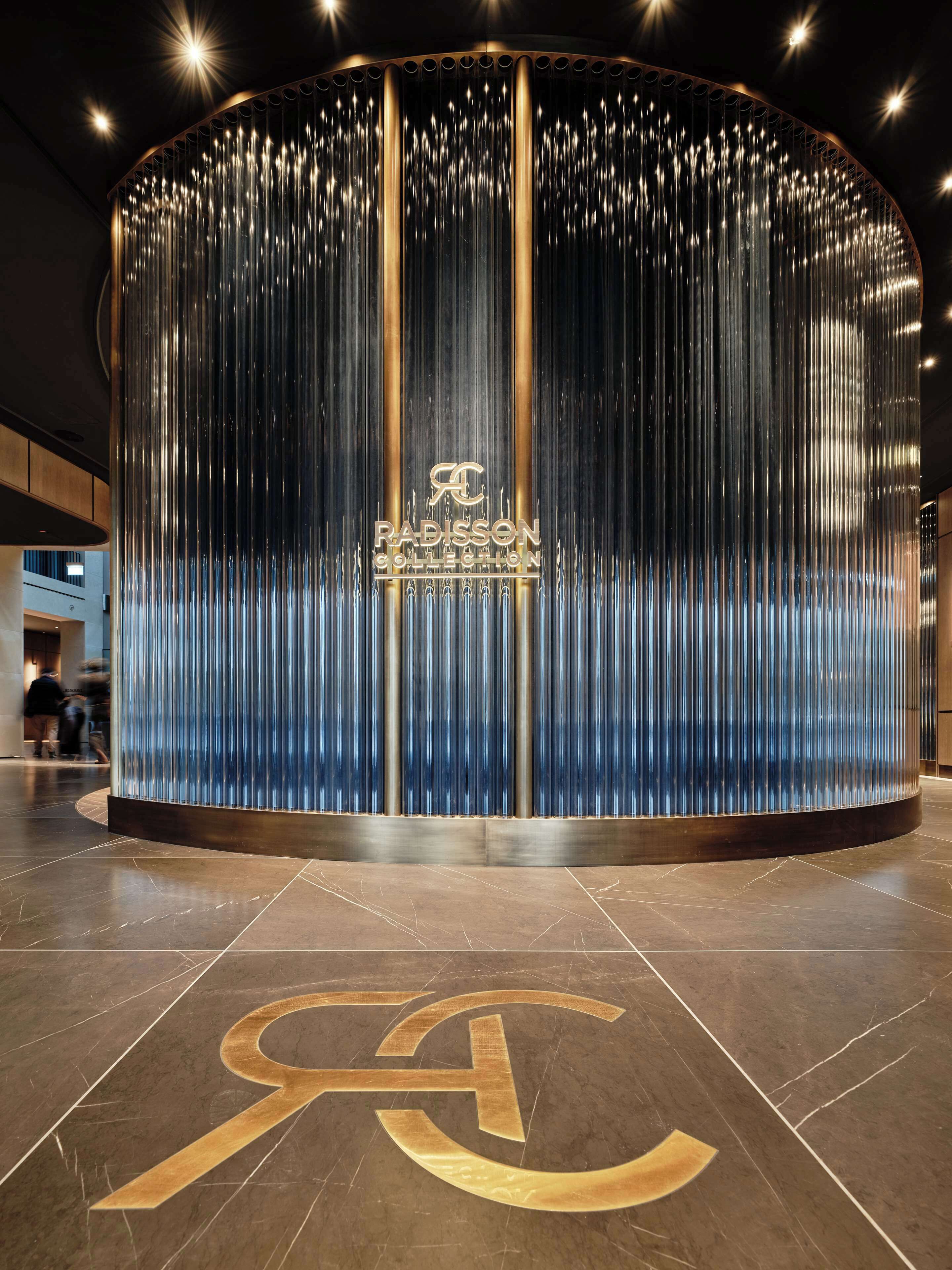 A modern building entrance with a metallic, vertical panel design and the "RADISSON COLLECTION" logo.