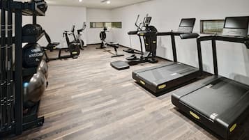 Un gimnasio moderno con cintas de correr, elípticas y equipos de levantamiento de pesas.