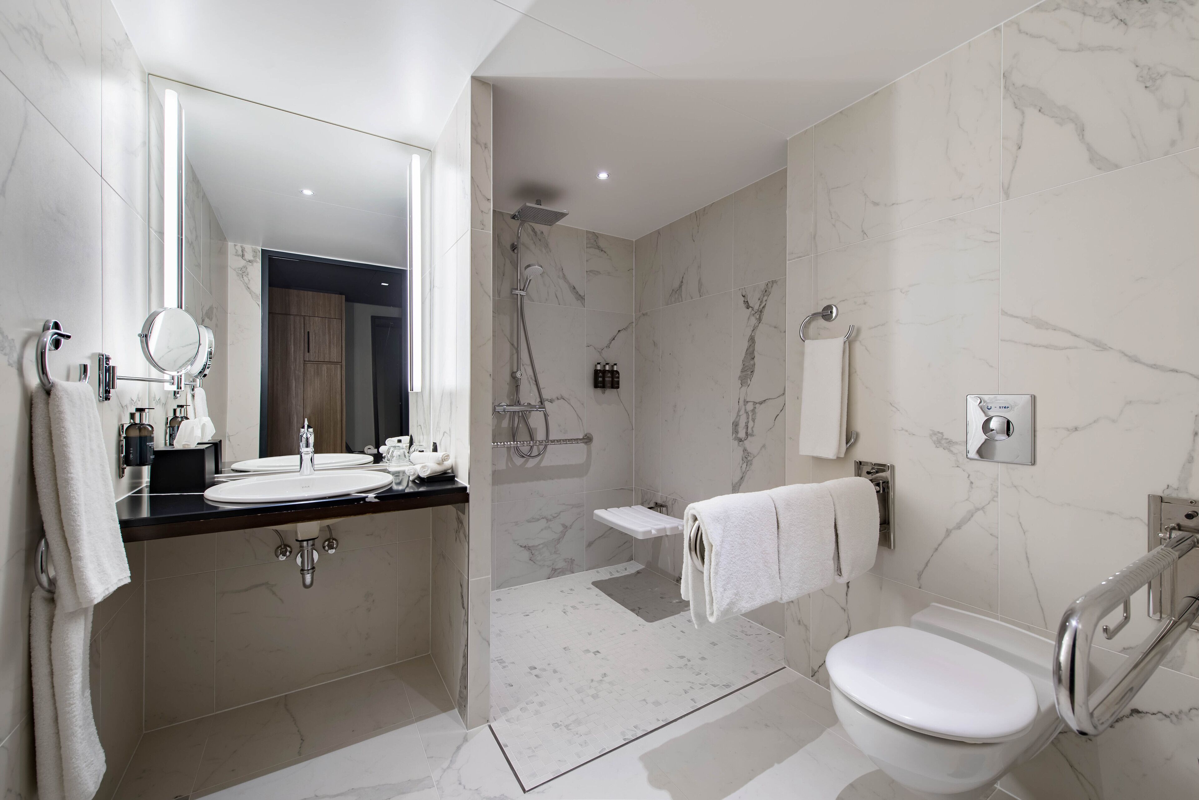 A modern bathroom with a large mirror, a sink, a toilet, and a shower area.