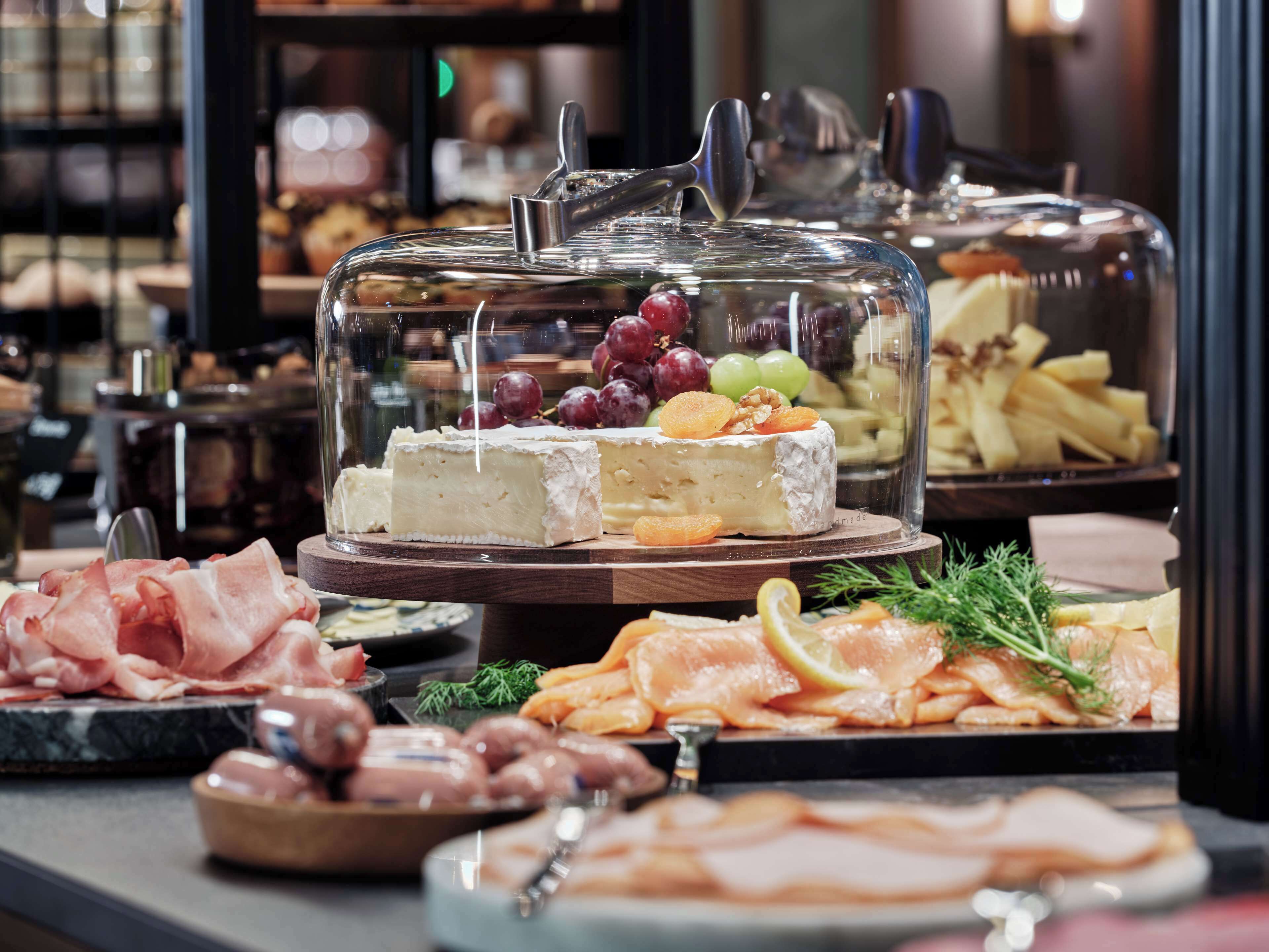 A buffet with various cheeses, meats, and fruits.