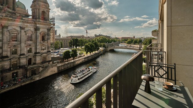 A river with a boat, a bridge, and historic buildings in the background.