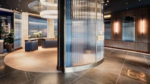 A modern lobby with a reception desk, a chandelier, and a vertical light panel.