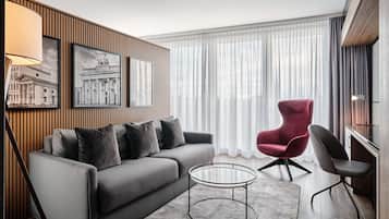 A modern living room with a grey sofa, a red armchair, a glass coffee table, and a lamp.